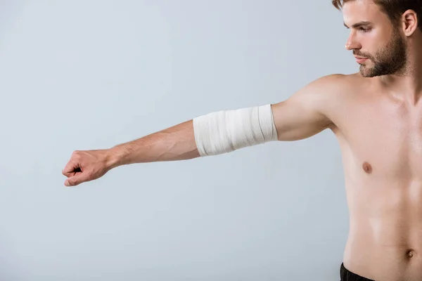 Vue partielle du sportif torse nu avec bandage élastique sur le coude isolé sur gris — Photo de stock