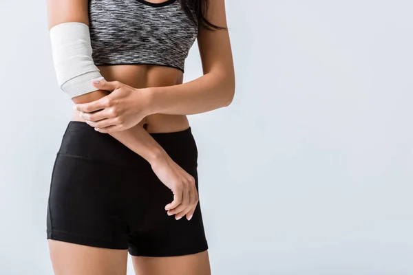 Partial view of sportswoman with elastic bandage on elbow isolated on grey — Stock Photo