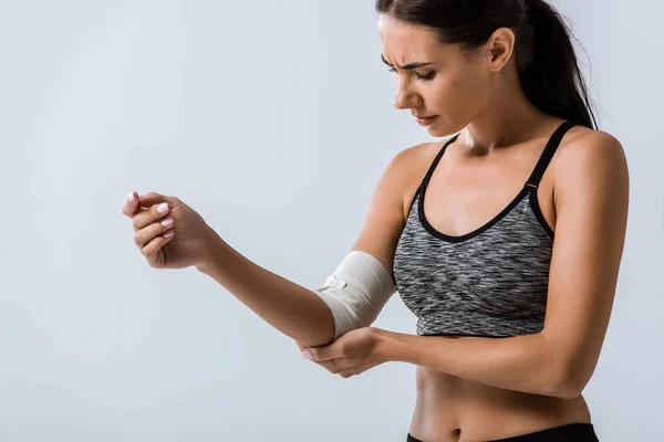 Sportlerin mit elastischem Verband am Ellbogen isoliert auf grau — Stockfoto