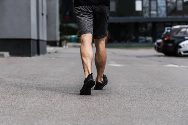 Partial view of sportsman in black sneakers walking on street — Stock Photo