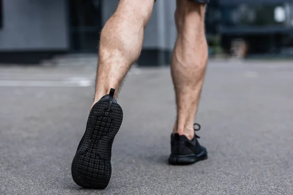 Partial view of sportsman in black sneakers walking on street — Stock Photo