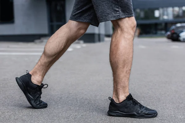 Vista parcial del deportista en zapatillas negras caminando por la calle - foto de stock