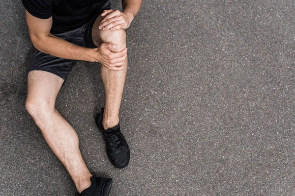 Vista parziale dello sportivo con dolore al ginocchio sulla strada — Foto stock