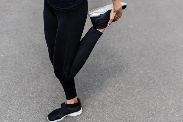 Partial view of sportswoman in black sneakers warming up on street — Stock Photo