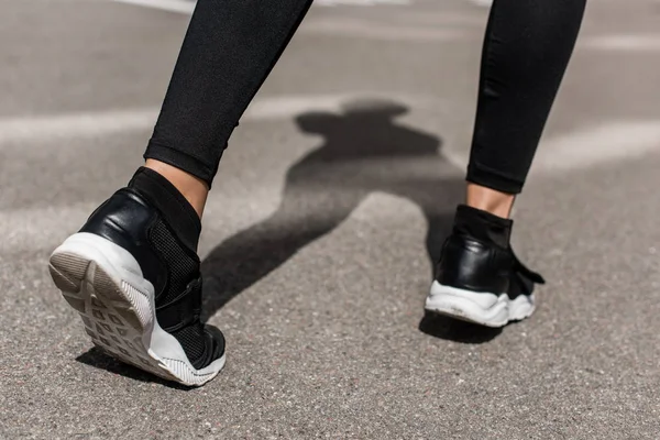 Cropped view of sportswoman in black sneakers on street — Stock Photo