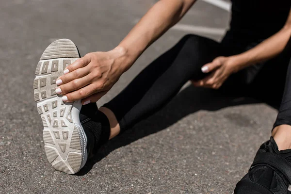 Vista parziale di sportiva con dolore alle gambe che si estende sulla strada — Foto stock