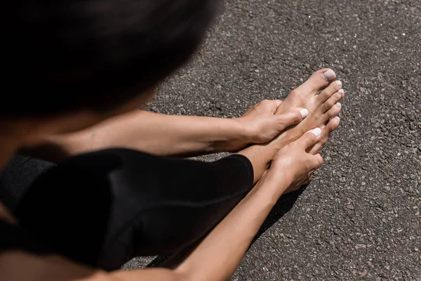 Partial view of barefoot sportswoman with foot pain on street — Stock Photo
