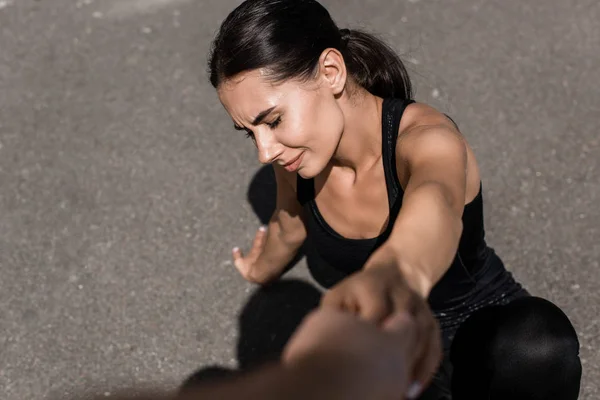 Vue partielle de l'homme aidant la sportive dans la rue — Photo de stock