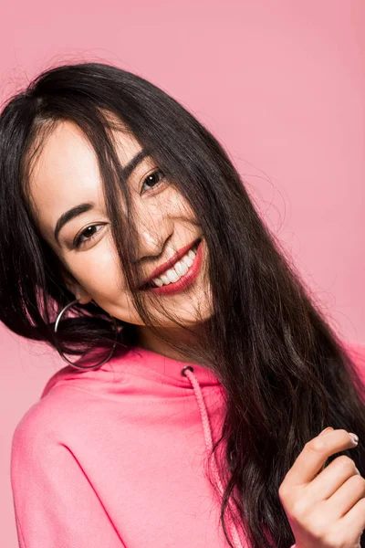 Attractive asian woman in pink pullover smiling isolated on pink — Stock Photo