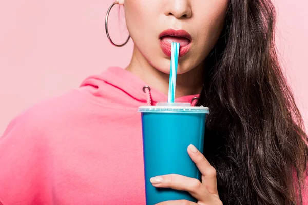 Cropped view of woman in pullover drinking from plastic cup isolated on pink — Stock Photo