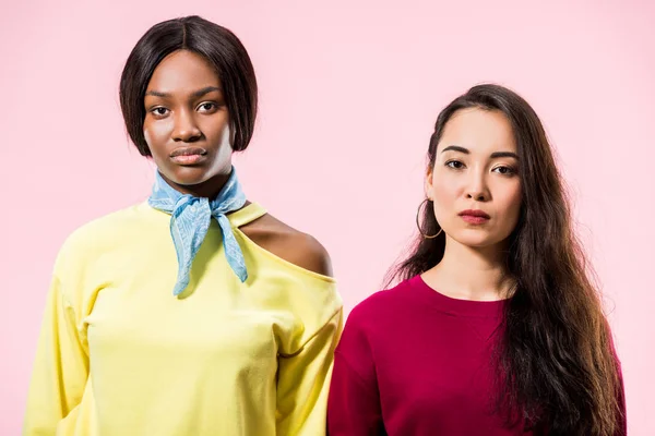 Attractive asian and african american friends looking at camera isolated on pink — Stock Photo