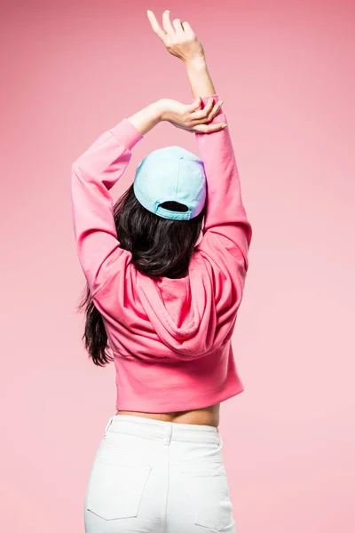 Vista posteriore della donna in pullover rosa e cappuccio che tiene le mani isolate su rosa — Foto stock