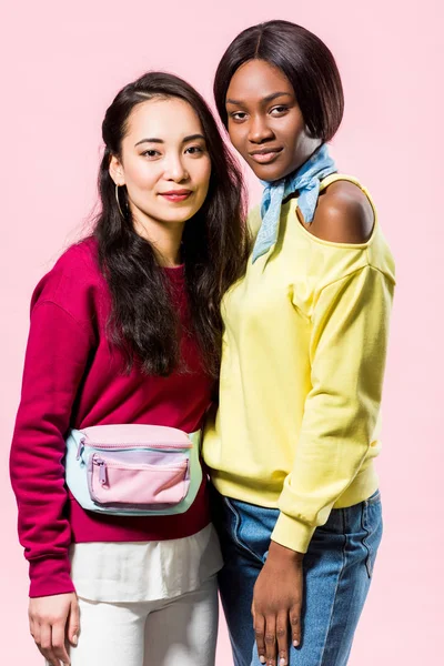 Attractive asian and african american friends smiling isolated on pink — Stock Photo