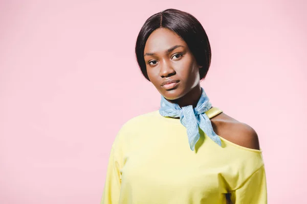 Donna afroamericana in pullover giallo e sciarpa guardando la fotocamera isolata su rosa — Foto stock
