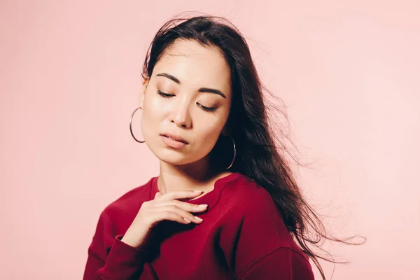 Attraktive asiatische Frau im roten Pullover mit geschlossenen Augen isoliert auf rosa — Stockfoto