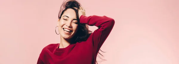 Panoramic shot of attractive asian woman in red sweater smiling isolated on pink — Stock Photo