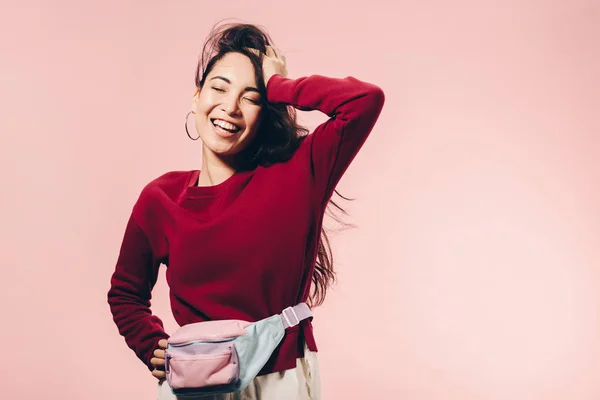 Attraktive asiatische Frau in rotem Pullover mit geschlossenen Augen, die isoliert auf rosa lächelt — Stockfoto