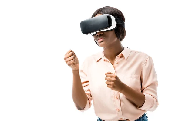 Mujer afroamericana en camisa con auriculares de realidad virtual que muestran puños aislados en blanco - foto de stock
