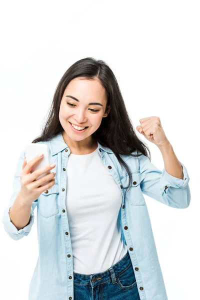Приваблива азіатська жінка в джинсовій сорочці, що показує так жест і тримає смартфон ізольовано на білому — стокове фото