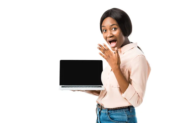Шокована афроамериканська жінка в сорочці тримає ноутбук з копіювальним простором ізольовано на білому — стокове фото