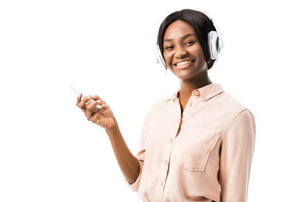 Sorrindo mulher americana africana na camisa com fones de ouvido segurando smartphone isolado no branco — Fotografia de Stock