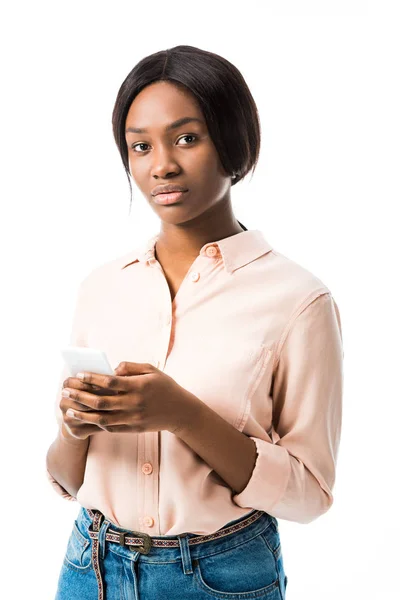 Mujer afroamericana en camisa sosteniendo teléfono inteligente aislado en blanco - foto de stock