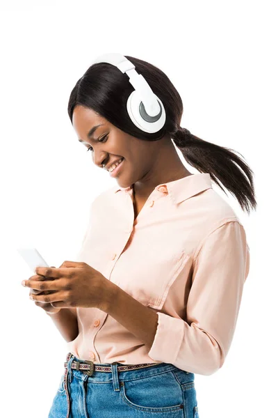 Femme afro-américaine souriante avec casque tenant smartphone isolé sur blanc — Photo de stock