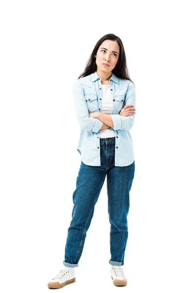 Atractiva y triste mujer asiática en camisa de mezclilla con brazos cruzados aislados en blanco - foto de stock