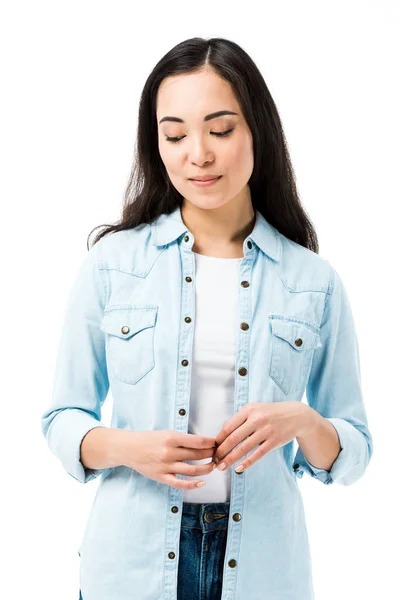 Привлекательная и застенчивая азиатка в джинсовой рубашке, смотрящая вниз изолированным на белом — стоковое фото