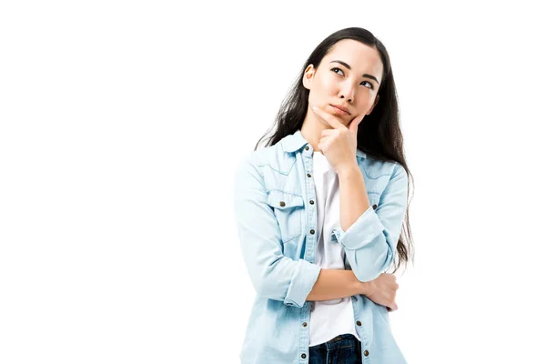 Attraktive und nachdenkliche asiatische Frau im Jeanshemd, die isoliert auf weißem Grund wegschaut — Stockfoto