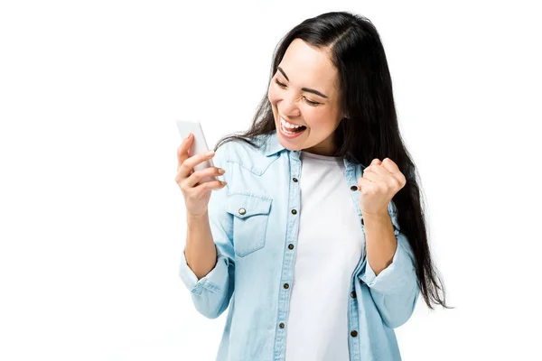 Attrayant et souriant asiatique femme en denim chemise montrant oui geste et tenant smartphone isolé sur blanc — Photo de stock