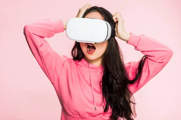 Schockierte Frau in rosa Pullover mit Virtual-Reality-Headset isoliert auf rosa — Stockfoto