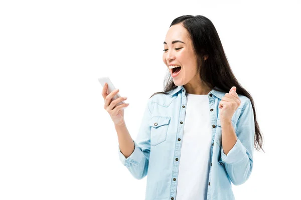 Attrayant et souriant asiatique femme en denim chemise tenant smartphone et montrant oui geste isolé sur blanc — Photo de stock