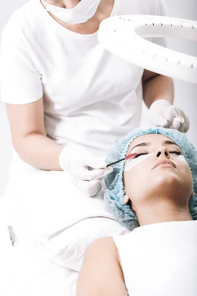 Eyelash master brushing false eyelashes on model face — Stock Photo