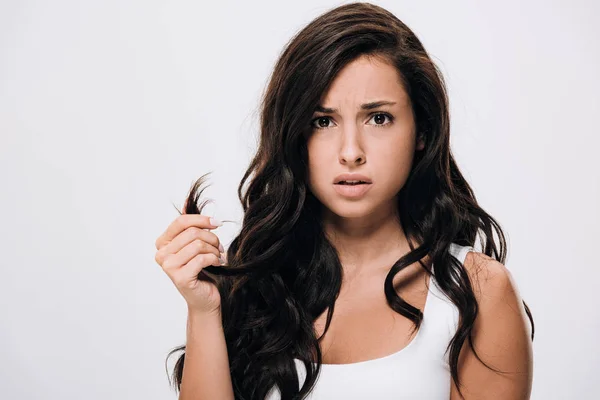 Confused brunette beautiful woman showing damaged hair isolated on grey — Stock Photo