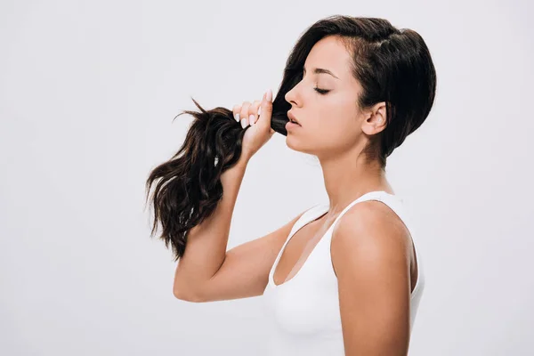 Vue latérale de brune belle femme tenant de longs cheveux sains et brillants isolés sur gris — Photo de stock