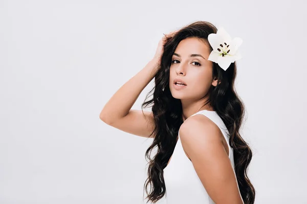 Brunette beautiful woman with lily in long healthy hair isolated on grey — Stock Photo