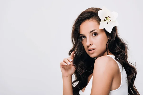 Brunette beautiful woman with lily in long healthy hair isolated on grey — Stock Photo