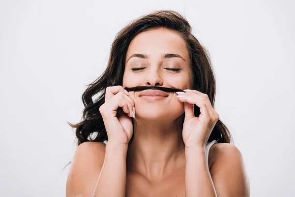 Pleased brunette beautiful woman with closed eyes making fake mustache from long healthy hair isolated on grey — Stock Photo