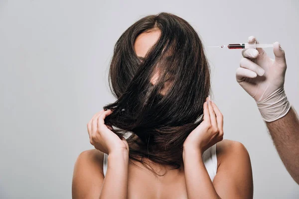 Cosmetologista em luvas de látex fazendo mesoterapia couro cabeludo para morena bela mulher com cabelos longos isolados em cinza — Fotografia de Stock