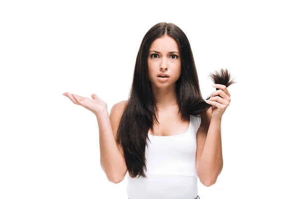 Mujer hermosa confundida mirando el pelo largo y recto dañado aislado en blanco - foto de stock