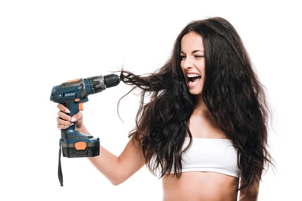 Brunette beautiful woman using hammer drill on hair and yelling isolated on white — Stock Photo