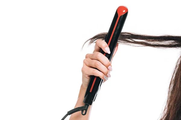 Cropped view of woman styling curly hair with flat iron isolated on white — Stock Photo