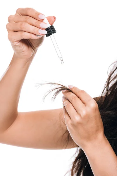 Vista parcial de morena hermosa mujer con el pelo dañado celebración de aceite aislado en blanco - foto de stock