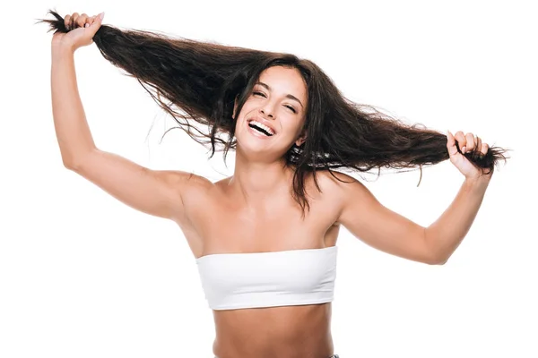 Happy brunette beautiful woman holding wavy hair isolated on white — Stock Photo