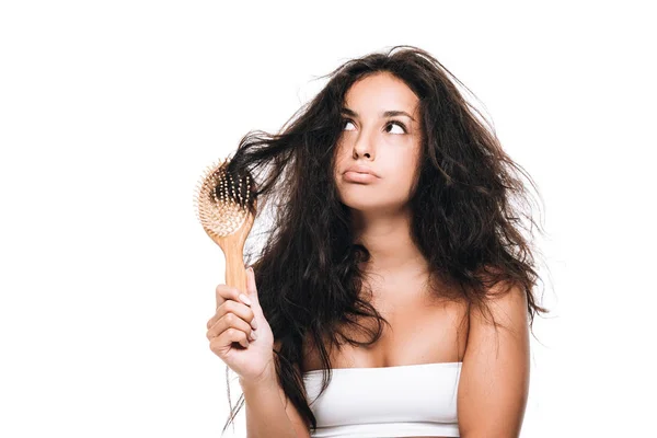 Gestresste brünette Frau mit welligem widerspenstigem Haar in Kamm, die isoliert auf weißem Grund wegschaut — Stockfoto