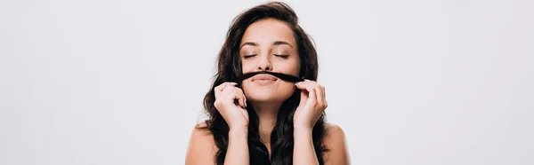 Panoramic shot of brunette beautiful woman with closed eyes making fake mustache from long healthy hair isolated on grey — Stock Photo