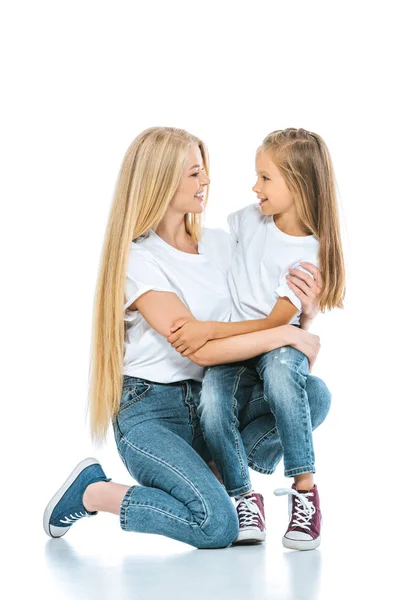 Счастливая мать и дочь обнимаются и смотрят друг на друга на белом — стоковое фото