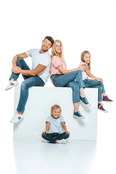 Familia feliz sentado en cubo y mirando a la cámara en blanco - foto de stock