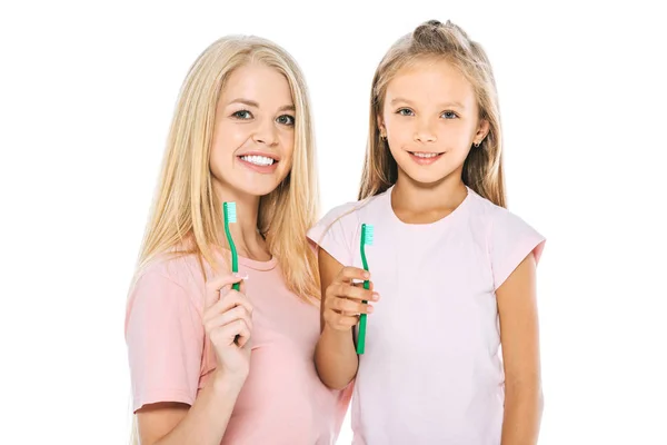 Щаслива мати і дочка тримають зубні щітки і дивляться на камеру ізольовано на білому — стокове фото